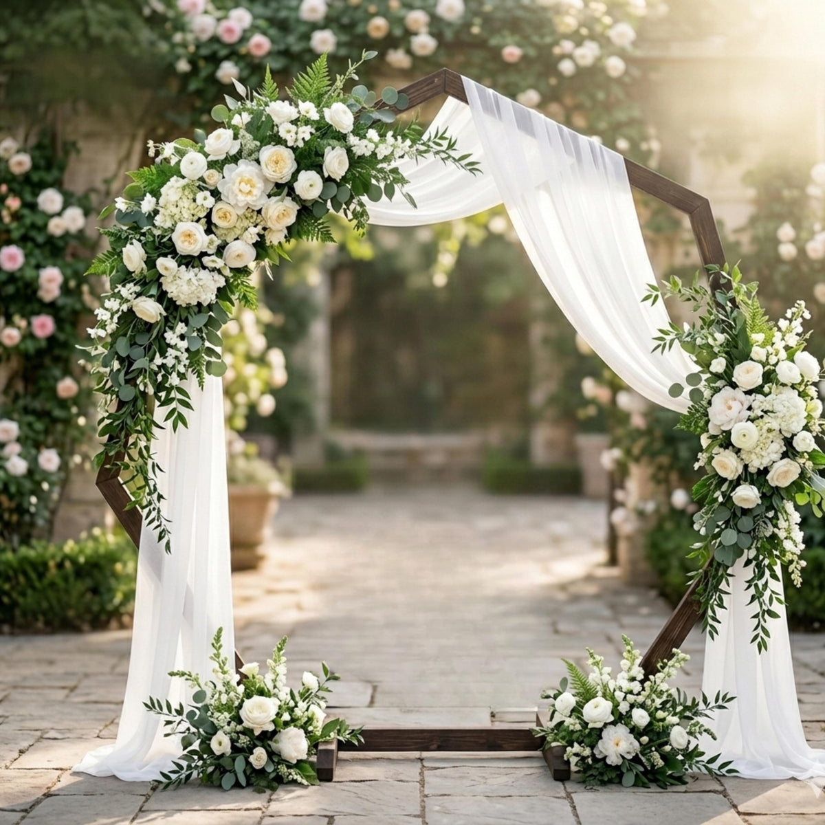 White floral wedding arch draped with ivory fabric in a garden ceremony setting