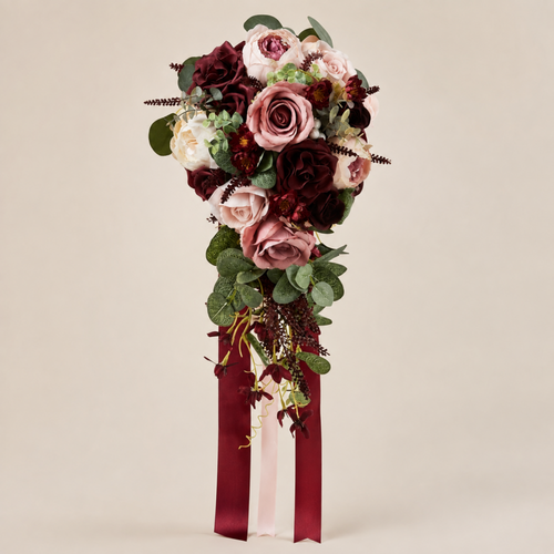 Burgundy and dusty rose cascading bridal bouquet with silk roses and trailing burgundy ribbon on a neutral background