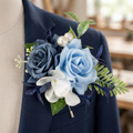 Dusty blue and navy rose boutonniere with white flowers and pearl accents pinned to a navy suit lapel