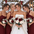 Bride in a fur stole with bridesmaids in burgundy dresses, all holding burgundy and ivory rose bouquets