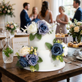 Blue and white silk rose cake topper on two tier wedding cake with artificial flowers and greenery