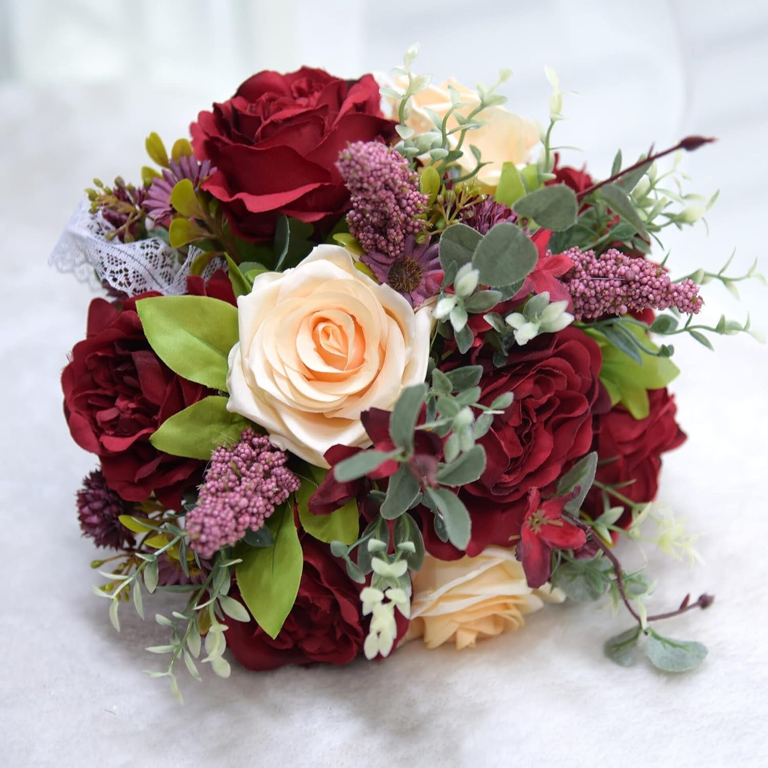 Close up of burgundy cascading wedding bouquet with greenery and ribbons