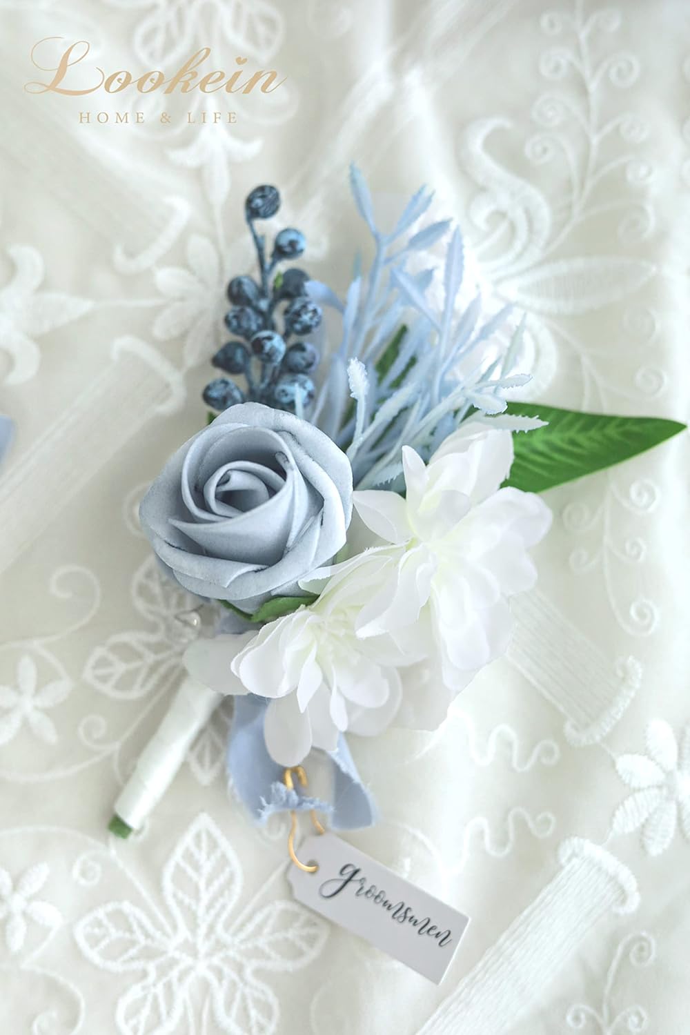 Close up of dusty blue boutonniere with white flower accents and greenery