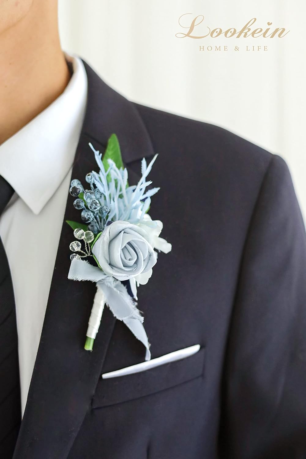 Dusty blue groom boutonniere pinned on black suit for wedding ceremony
