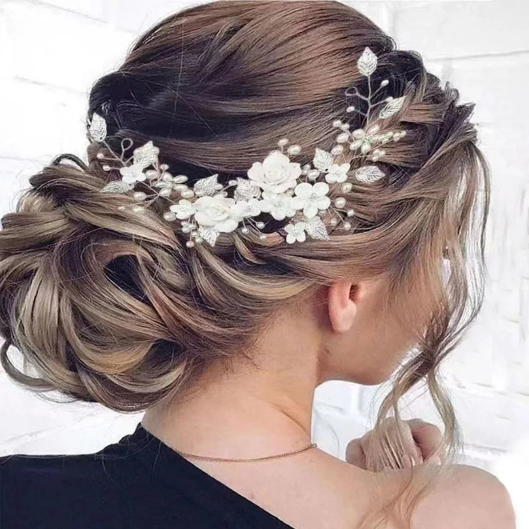 Romantic braided updo with a silver hair vine of white flowers, pearls and leaves woven along the side