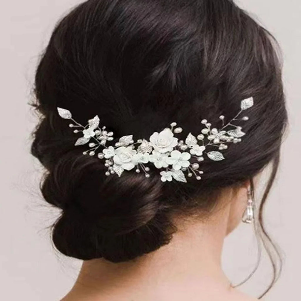 Bride's low bun from behind with a silver pearl and white flower hair vine pinned across it