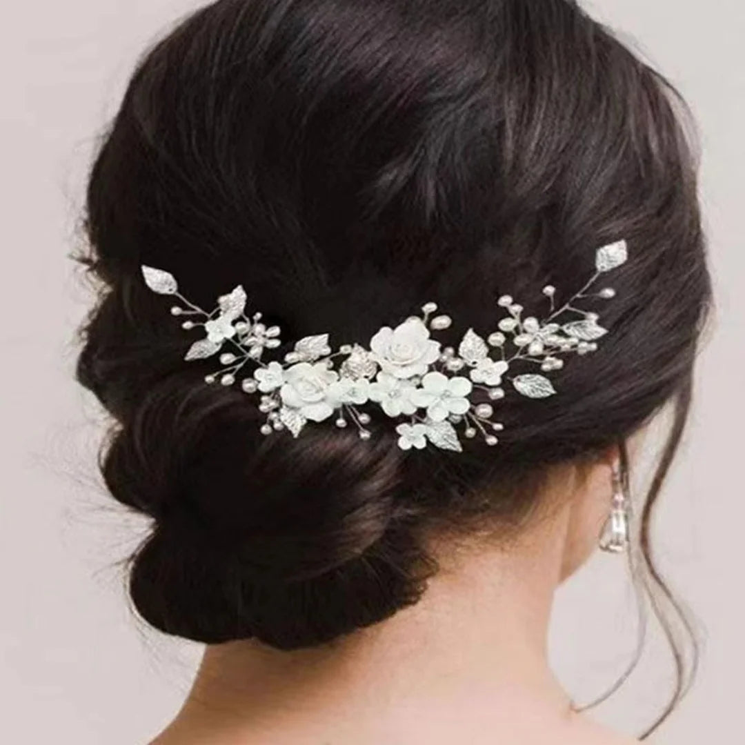 Bride's low bun from behind with a silver pearl and white flower hair vine pinned across it