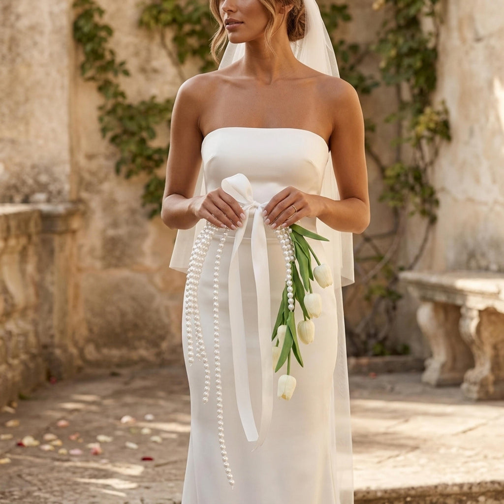 Bride holding pearl tulip bridal bouquet with cascading pearls and satin bow