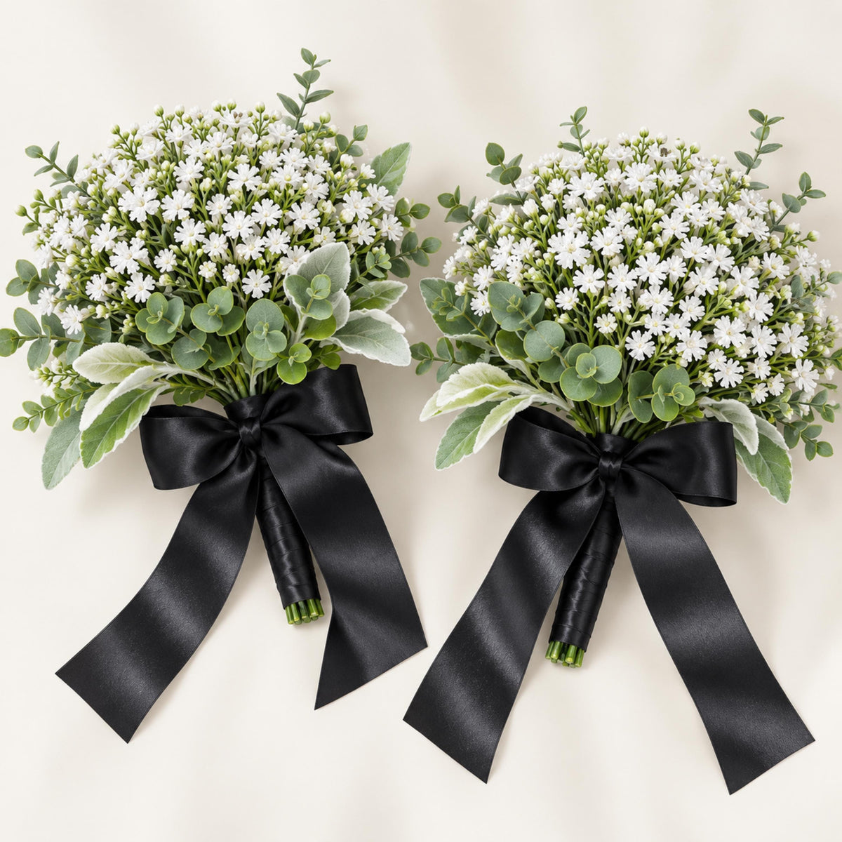 Two faux white gypsophila bridesmaid bouquets with sage greenery and black ribbon-wrapped handles