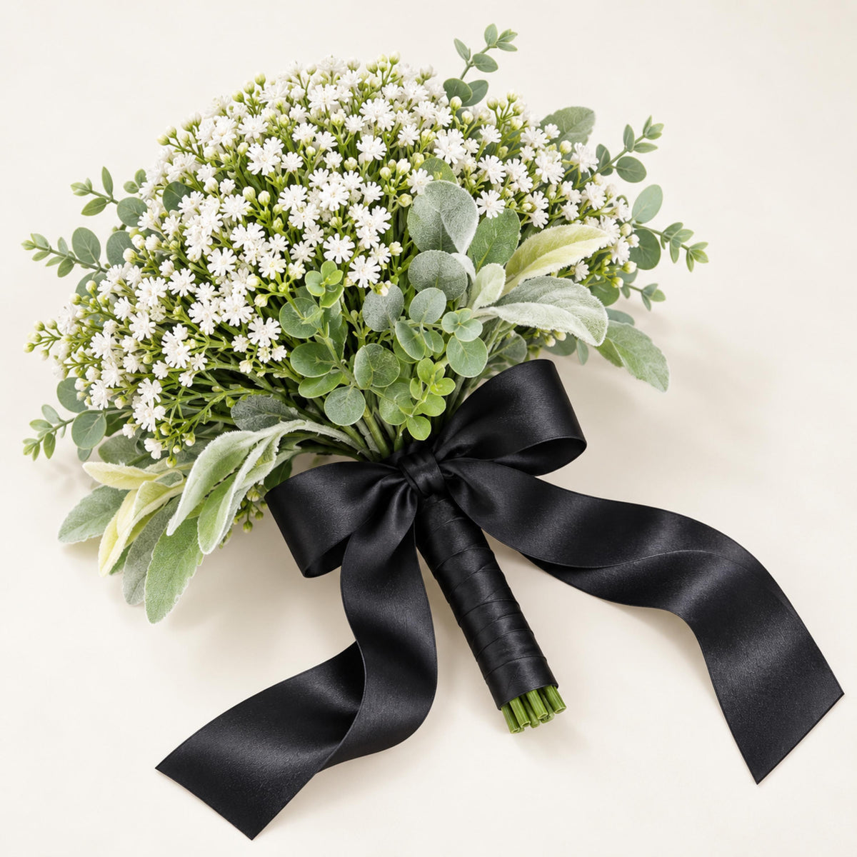 Close-up of a faux baby's breath bouquet with eucalyptus and lamb's ear leaves and a black satin bow
